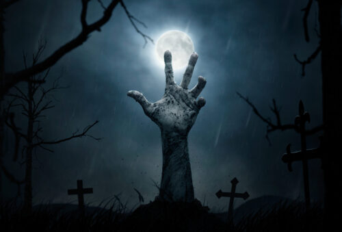 Zombie hand reaching out from grave with full moon in background
